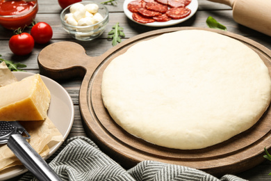 Dough and fresh ingredients for pepperoni pizza on wooden table