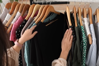 Woman choosing clothes from wardrobe rack, closeup