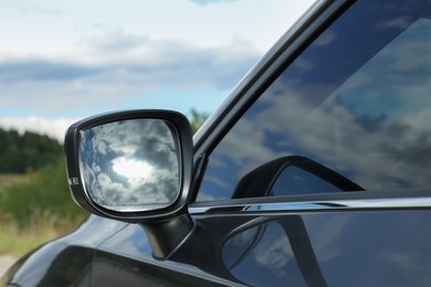 New black modern car outdoors, closeup of side rear view mirror