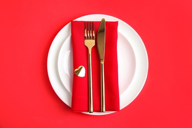 Beautiful table setting for romantic dinner on red background, top view. Valentine's day celebration
