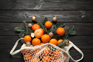 Photo of Flat lay Christmas composition with fresh tangerines in mesh bag on dark wooden table
