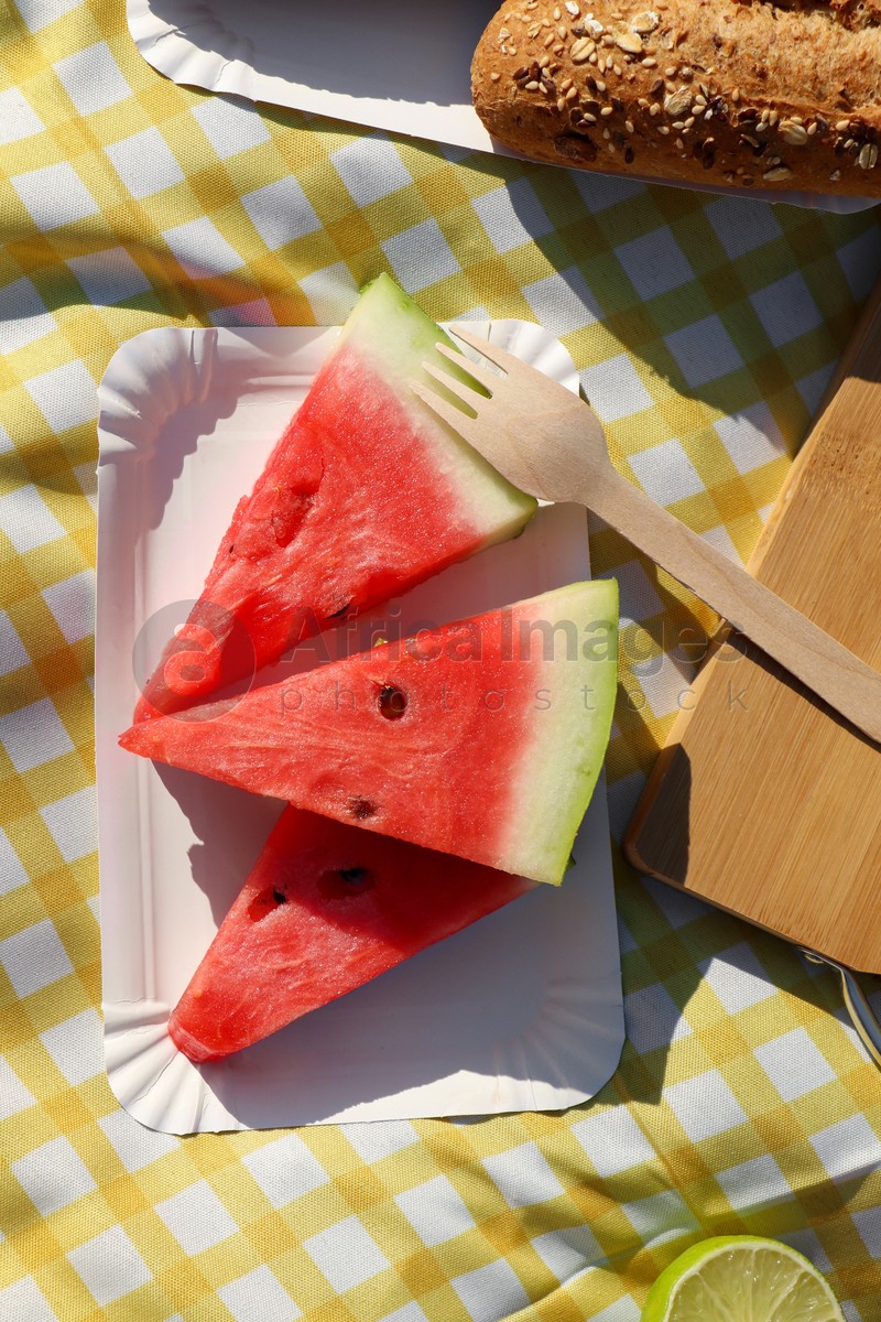 Delicious watermelon and bread on picnic blanket, flat lay