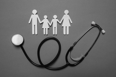 Photo of Paper family figures and stethoscope on grey background, flat lay. Insurance concept