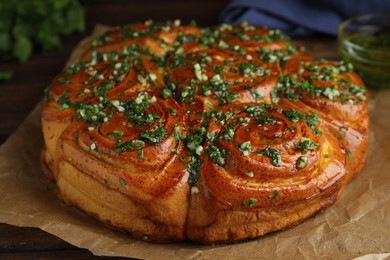 Photo of Traditional Ukrainian garlic bread with herbs (Pampushky) on wooden table, closeup