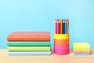 Composition with different school stationery on wooden table against light blue background. Back to school
