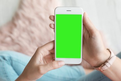 Image of Chroma key compositing. Woman holding smartphone with green screen indoors, closeup. Mockup for design