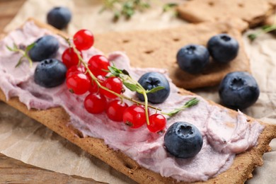 Tasty crispy crackers with cream cheese, thyme and berries, closeup