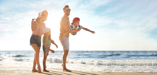 Happy family having fun on sandy beach near sea, space for text. Banner design