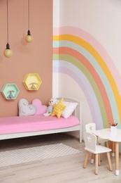 Photo of Cute child's room interior with beautiful rainbow painted on wall