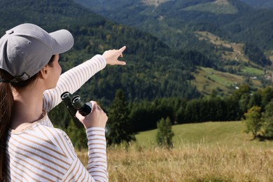 Woman with binoculars in mountains on sunny day