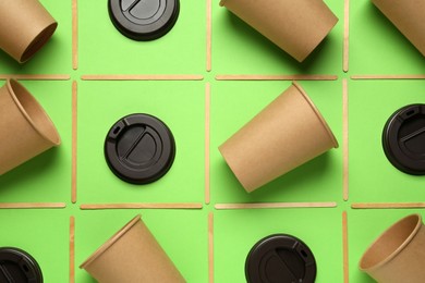 Photo of Paper cups, plastic lids and bamboo sticks on green background, flat lay. Eco friendly lifestyle