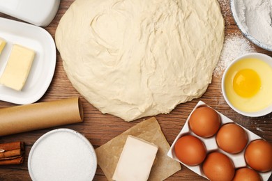 Photo of Fresh yeast dough and ingredients for cake on wooden table, flat lay