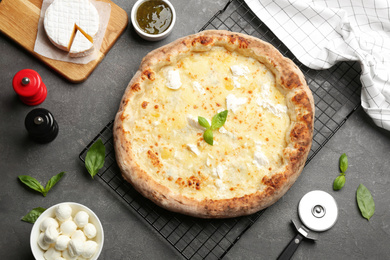 Photo of Delicious cheese pizza and fresh ingredients on grey table, flat lay