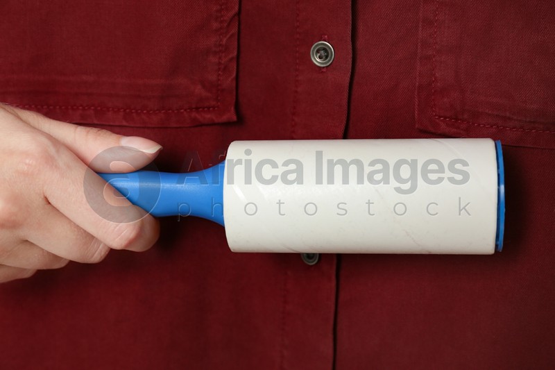 Photo of Woman cleaning red shirt with lint roller, closeup