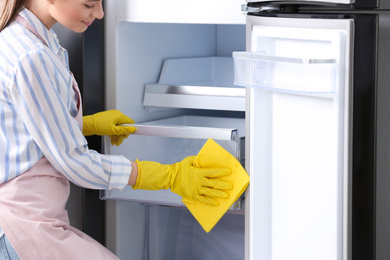 Woman in rubber gloves cleaning refrigerator, closeup