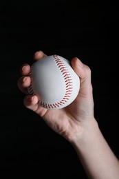 Photo of Baseball player holding ball on black background, closeup. Sports game