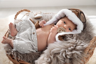 Photo of Adorable newborn baby with pacifier in wicker basket