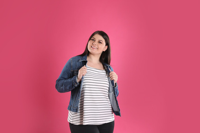 Beautiful overweight woman posing on pink background. Plus size model