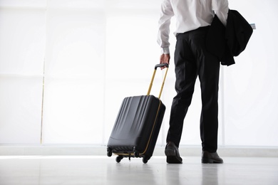Businessman with black travel suitcase in airport. Space for text
