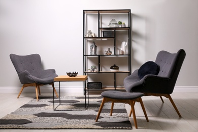 Photo of Stylish room with armchairs, coffee table and shelving. Interior design