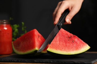 Woman cutting delicious watermelon on slate board, closeup