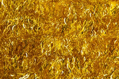 Shiny golden tinsel as background, top view