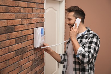 Man with handset answering intercom call indoors