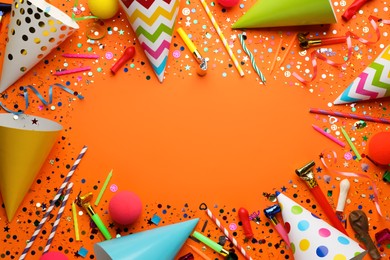 Frame of festive items on orange background, flat lay with space for text. Surprise party concept