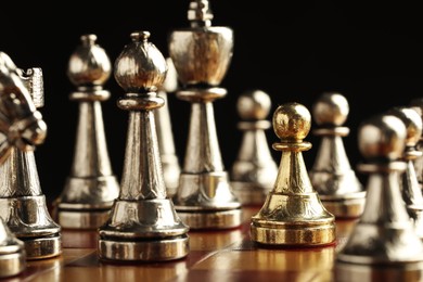 Chessboard with game pieces on black background, closeup