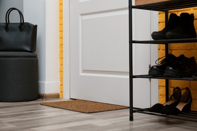 Door mat and shelving unit with shoes in hallway