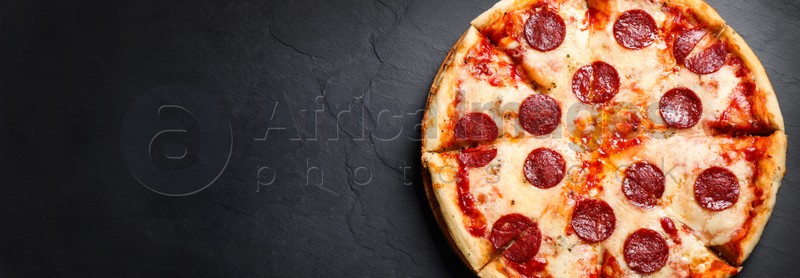 Image of Top view of hot delicious pizza on dark table, space for text. Banner design 