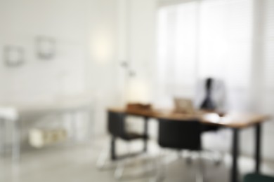 Blurred view of modern medical office with doctor's workplace and examination table. Interior design