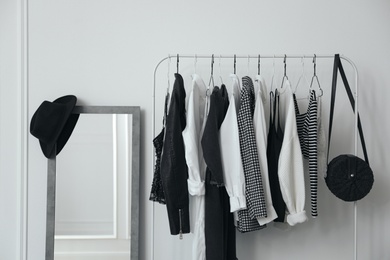 Rack with stylish clothes near white wall in dressing room