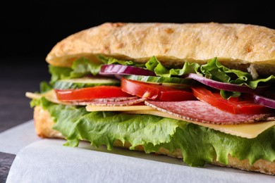 Photo of Delicious sandwich with fresh vegetables and salami on table, closeup