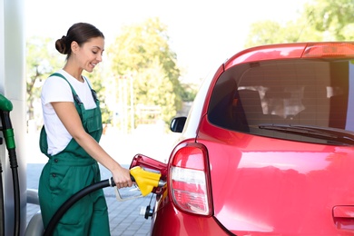 Photo of Young worker refueling car at modern gas station