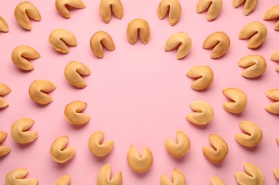 Photo of Frame of tasty fortune cookies with predictions on pink background, flat lay. Space for text