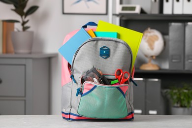 Children's backpack with different school stationery on table indoors
