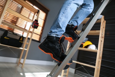 Person climbing ladder indoors, closeup on feet