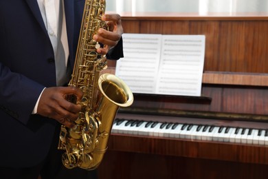 African-American man playing saxophone indoors, closeup with space for text. Talented musician
