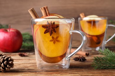Hot mulled cider and fir branches on wooden table, closeup