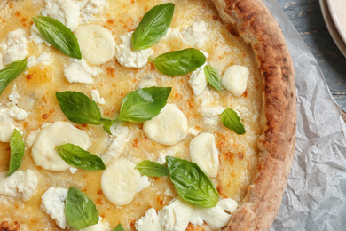 Photo of Delicious hot cheese pizza with basil on table, top view