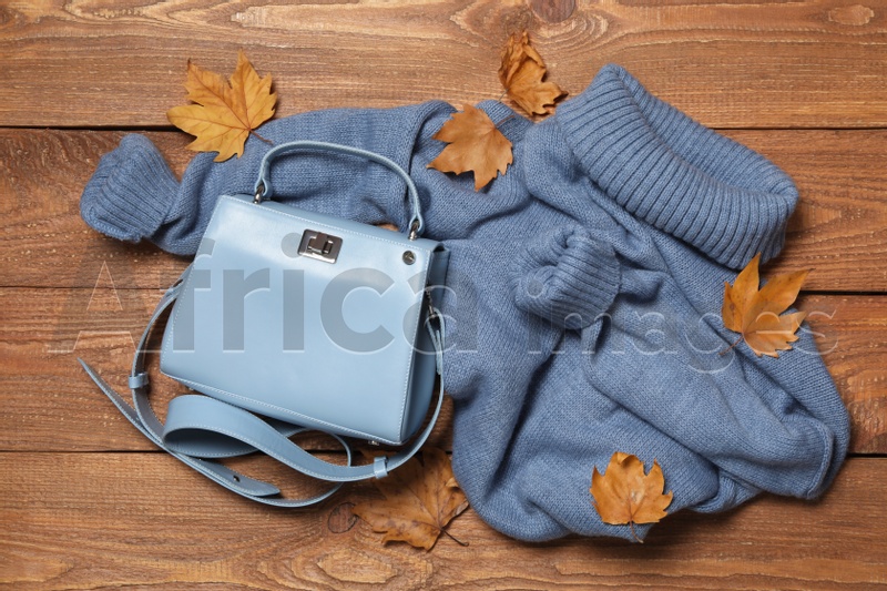 Photo of Warm sweater, bag and dry leaves on wooden background, flat lay. Autumn season