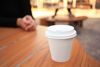 Photo of Cardboard cup with tasty coffee on table outdoors. Space for text