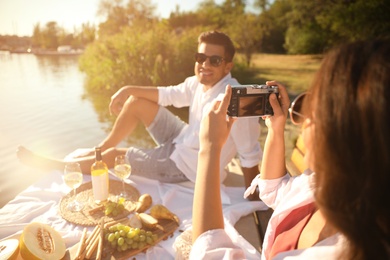 Woman taking picture of boyfriend on pier at picnic, closeup