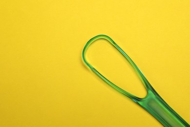 Green tongue cleaner on yellow background, top view. Space for text
