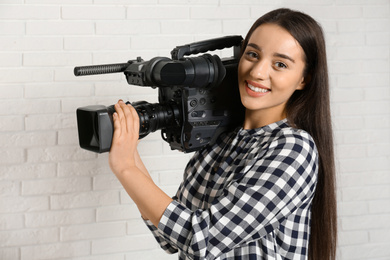 Operator with professional video camera near white brick wall