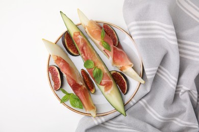Plate of tasty melon, jamon, and figs on white table, top view