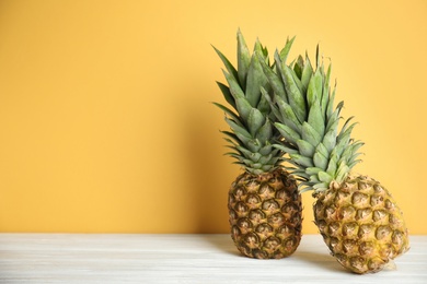 Photo of Fresh ripe juicy pineapples on white wooden table. Space for text