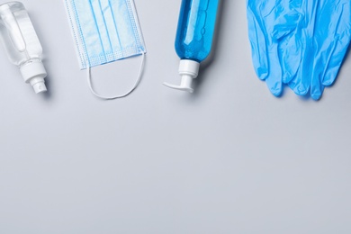 Medical gloves, mask and hand sanitizers on grey background, flat lay. Space for text