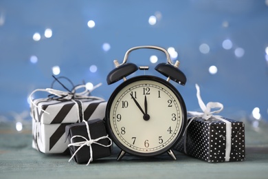Photo of Vintage alarm clock with decor on blue wooden table against blurred Christmas lights. New Year countdown